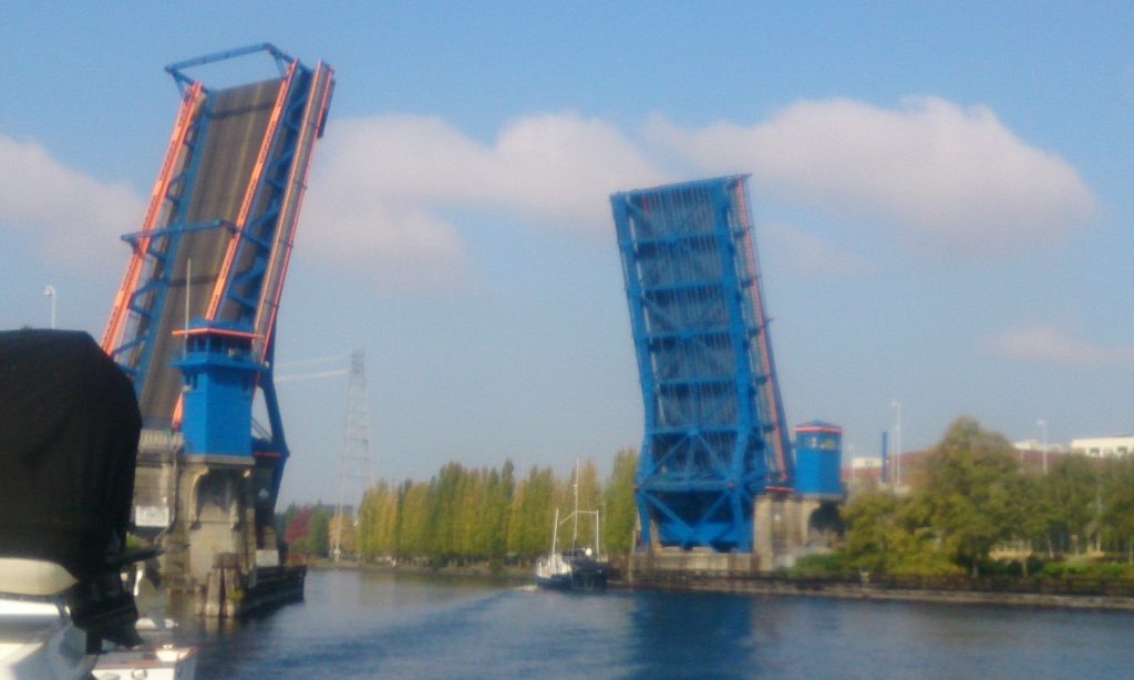 A boat throwing a good-sized wake heading through the Fremont Bridge to saltwater.